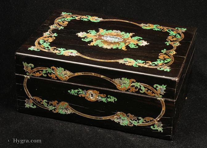 Antique fully fitted sewing box in almost black coromandel ebony profusely inlaid  to the top and front with engraved mother of pearl,  abalone, green parkesine, and brass. Inside there is the  lift-out tray  with its original purple velvet  coverings and supplementary lids. Inside the lid is lined with rushed cream coloured silk framed with gold embossed silk framing There is a document wallet behind.  The box has mother of pearl handled sewing tools and turned and carved mother of pearl spools. Parkeseine was the invention of Alexander Parks of Birmingham and was manufactured in his factory in Hackney. It is generally accepted as being the first plastic and was the predecessor of the American invention of celluloid which was similar but about 10 years later.  Enlarge Picture